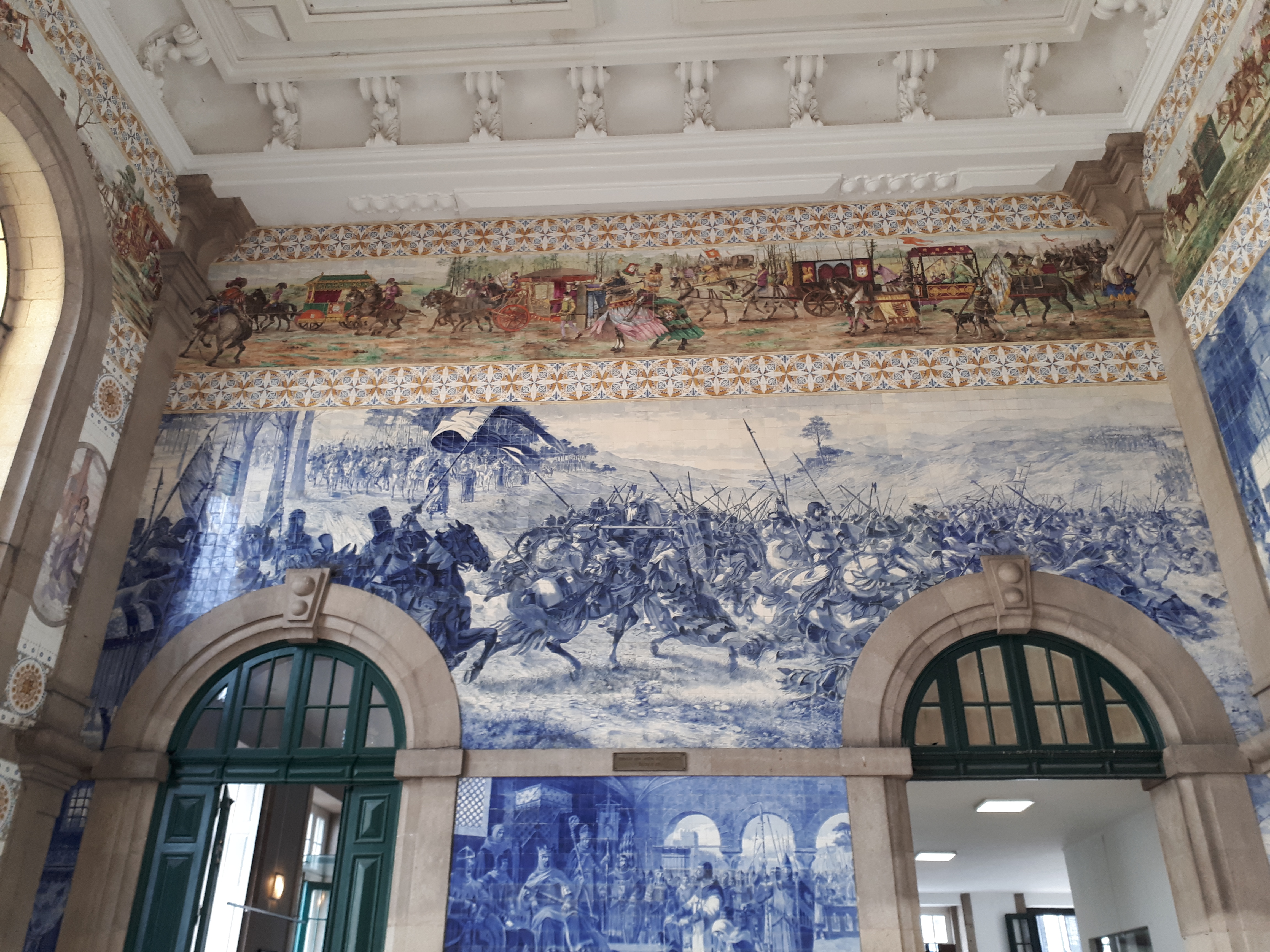 Entrada de una estación de trenes cuya pared está repleta de azulejos.