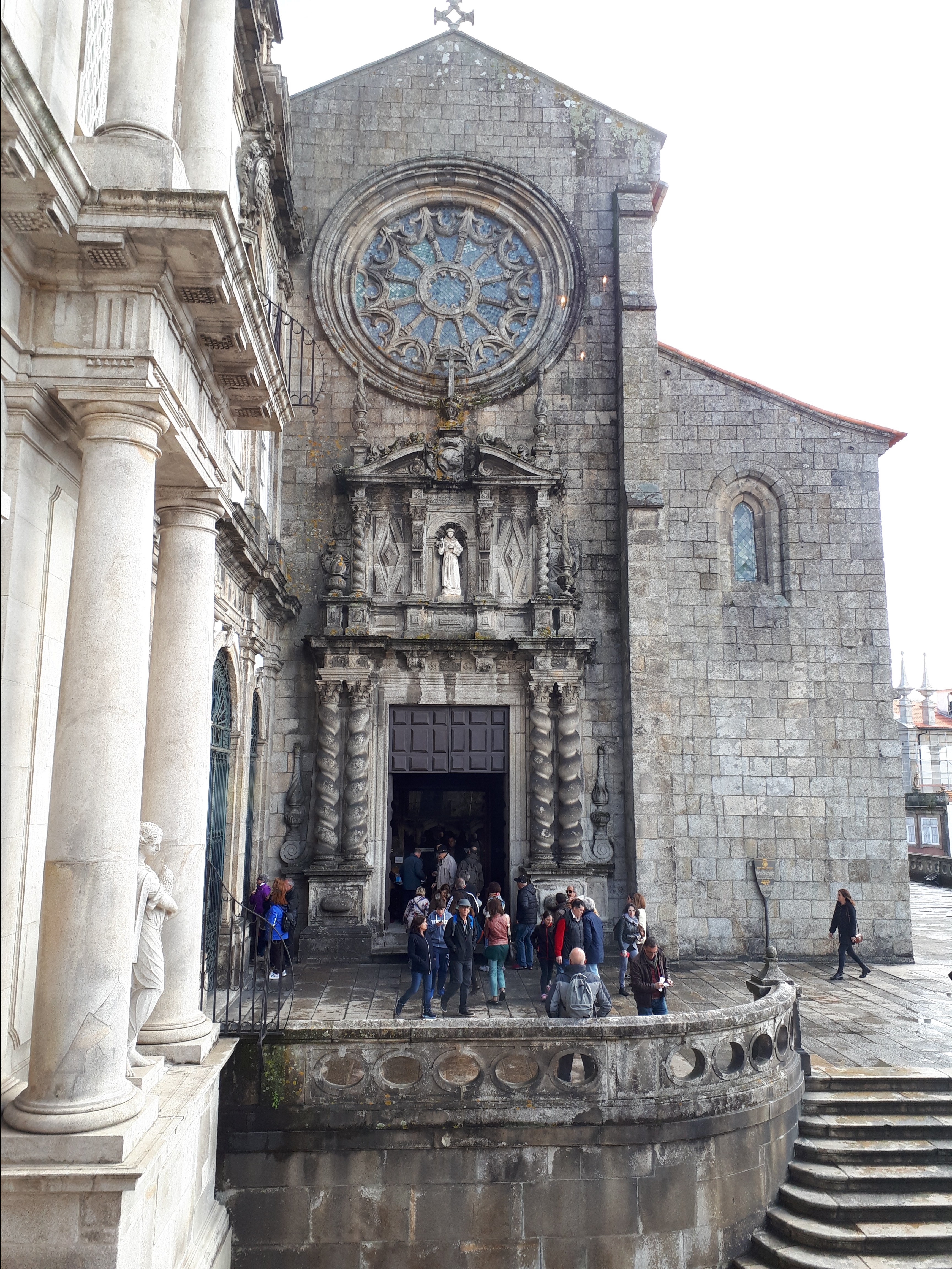 Iglesia gótica con una gran roseta encima de la puerta. Varias personas se esperan frente a su entrada.