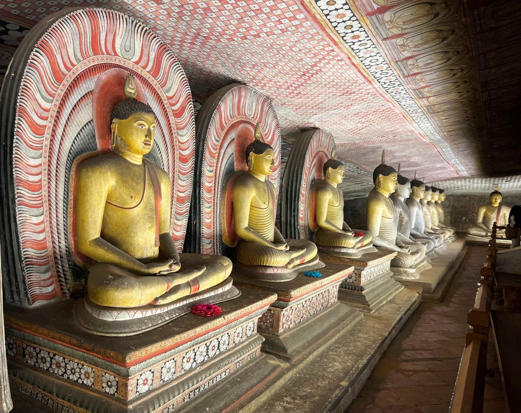 Hilera de budas en el interior de las Cuevas de Dambulla, uno de los lugares más impresionantes de ver y una de las visitas imprescindibles que hacer en Sri Lanka.