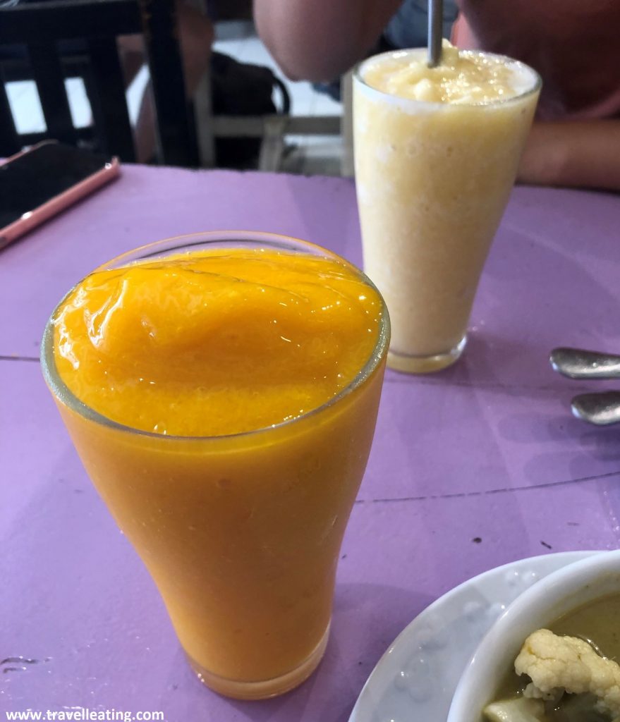 Zumos de mango y piña servidos en vasos alargados.