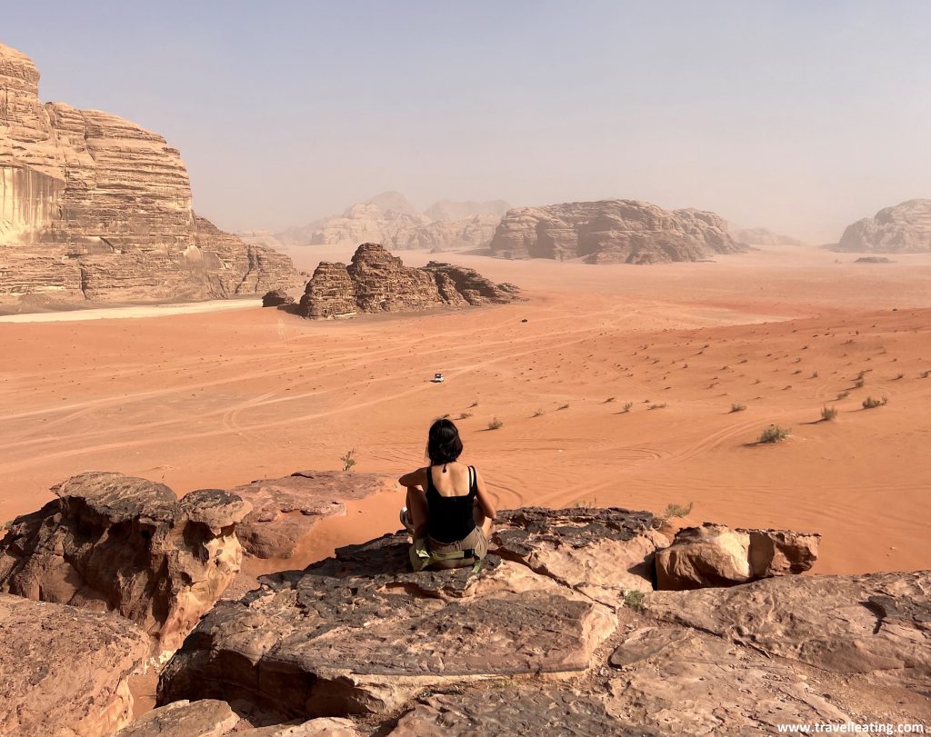Chica sentada frente a un espectacular paisaje desértico con grandes peñascos de roca. Otro de los imprescindibles que ver al viajar a Jordania.