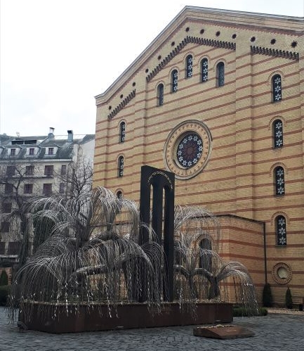 Sinagoga que presenta un monumento delante en forma de árbol de acero.