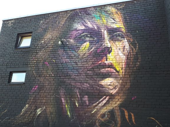 Precioso mural con tonos lilas que muestran las facciones de una mujer.