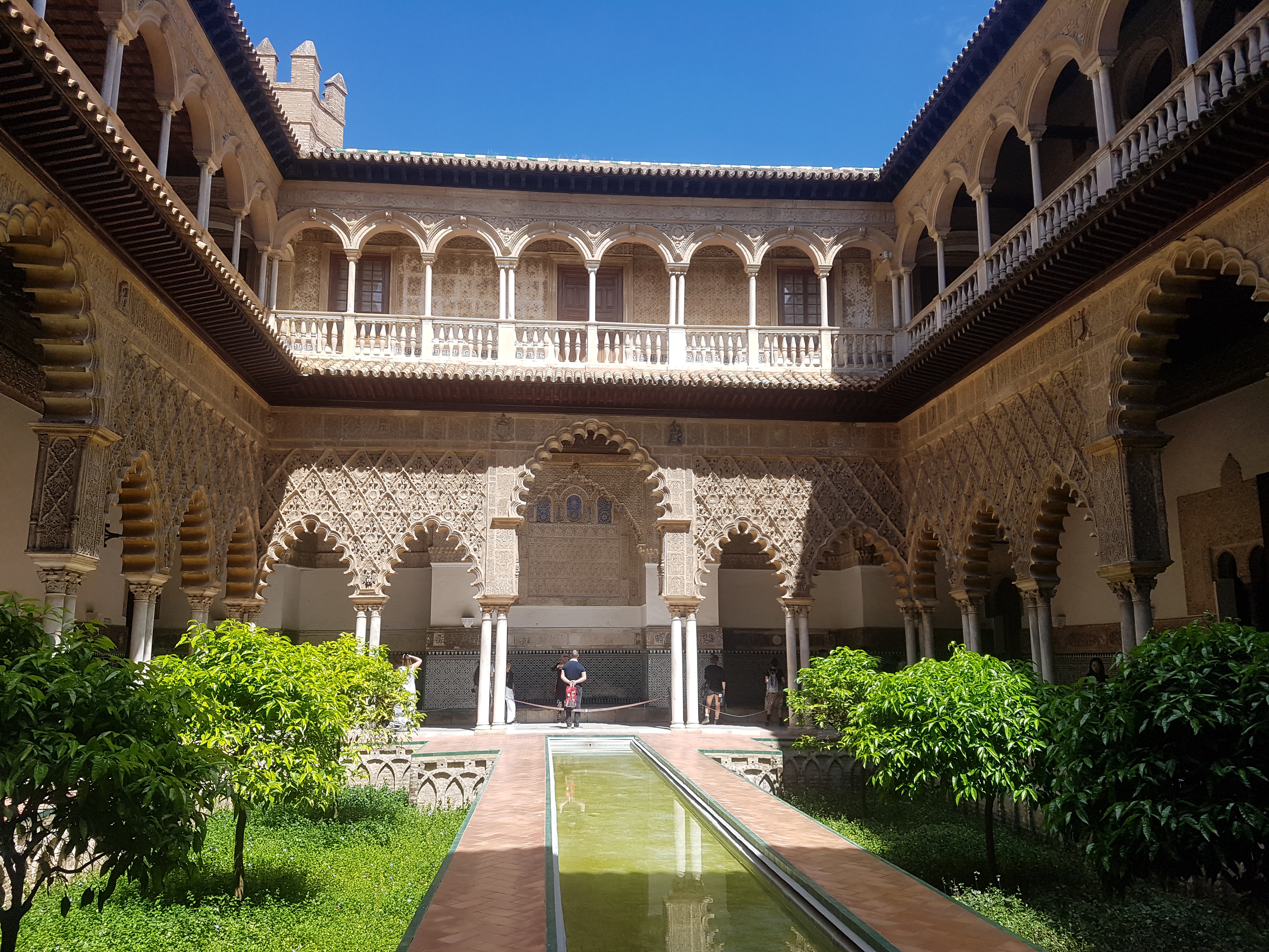 Patio árabe del Real Alcázar de Sevilla, con arcos, plantas y una fuente. Uno de los imprescindibles que visitar en Sevilla.
