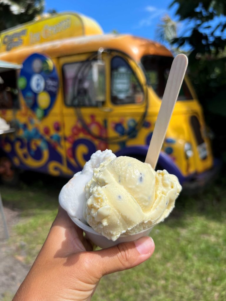Helado de coco del Coconut Glen’s Icecream, frente a su caravana amarilla pintada de colores.
