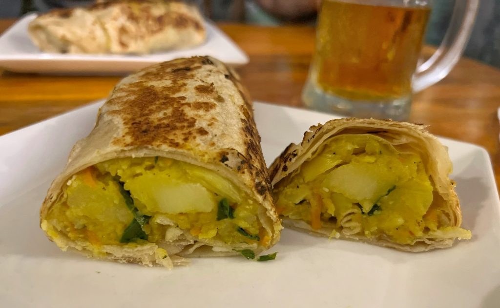 Roti relleno con curry de verduras y patatas y enrollado como un wrap.